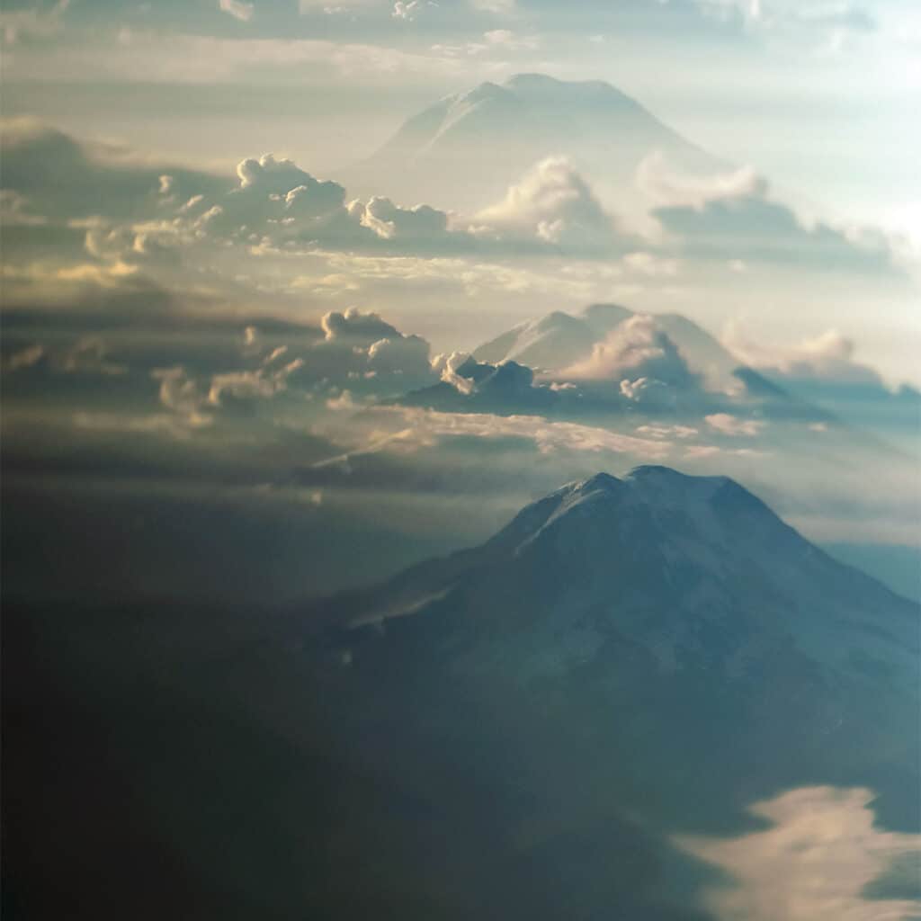 Photograph of Mount Rainier rising above the Seattle skyline, with layered clouds and architectural silhouettes in the foreground.