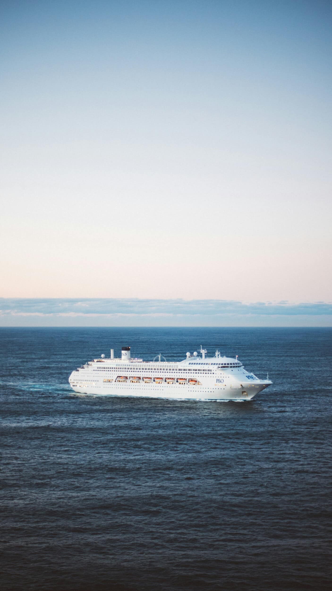 Cruise ship sailing across open water beneath a pale sky